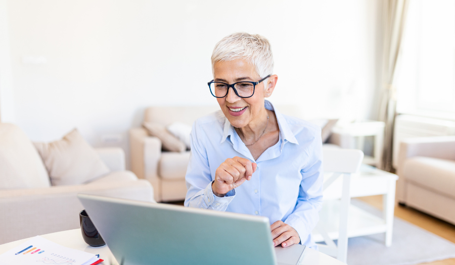 A women wearing glasses smiles at her laptop computer