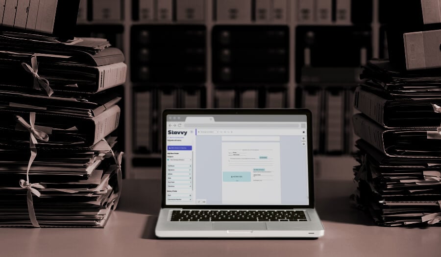 A laptop open to mortgage closing document esigning that is sitting between stacks of paper documents